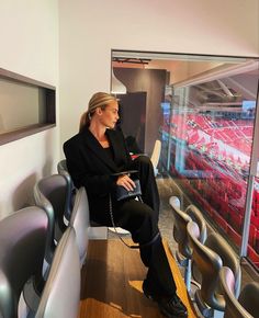 a woman sitting on a bench in front of a wall with red seats and lights