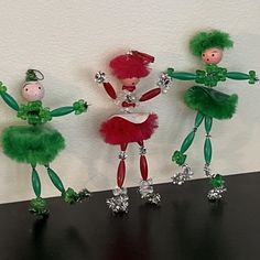 three green and red dolls standing next to each other on top of a black table