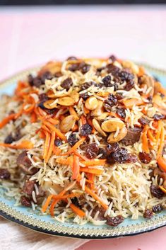 a plate full of carrots, raisins and rice on a pink table cloth