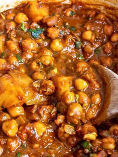 a pot filled with chickpeas and sauce on top of a wooden spoon