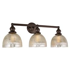 three light bathroom fixture with glass shades on the top and bottom, in an antique bronze finish