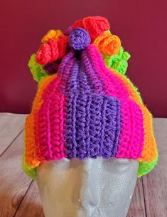 a knitted hat with multicolored flowers on top of a mannequin head