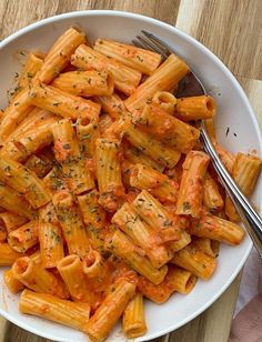 a white bowl filled with pasta on top of a wooden table