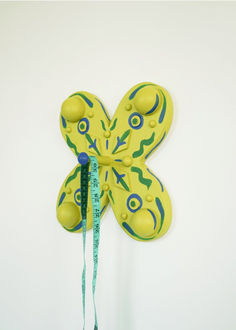 a yellow butterfly shaped clock hanging on the wall with a measuring tape attached to it