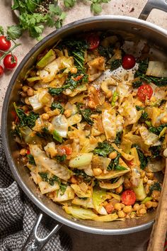 a pan filled with vegetables on top of a table next to tomatoes and parsley