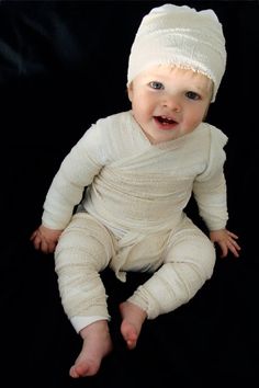 a baby wearing a white knitted outfit and a hat on top of it's head