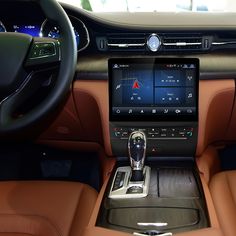 the interior of a car with an entertainment system and steering wheel control in front of it