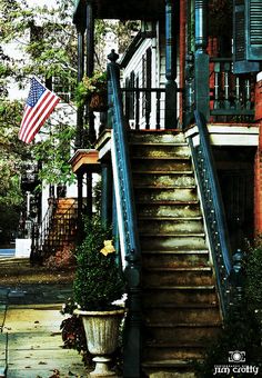 an american flag flying in front of a building with stairs leading up to the second floor