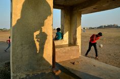 two people are playing with a ball in an abandoned building while another person looks on