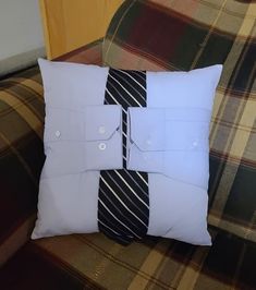 a white pillow with a black and white tie on it sitting on a plaid couch