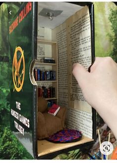 a hand is holding an open book in the shape of a box