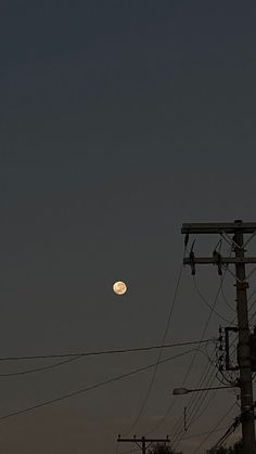 the full moon is visible over power lines