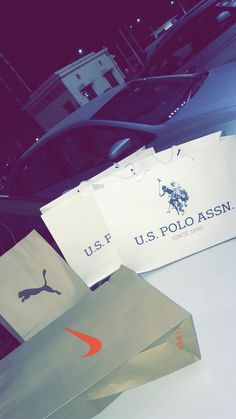 several shopping bags sitting on top of a white table next to a black and red car