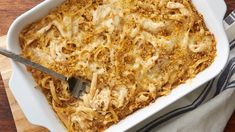 a casserole dish with meat and cheese in it on a wooden table next to a fork