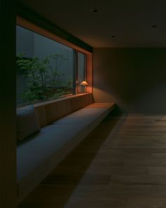 an empty room with wood flooring and large window overlooking the trees outside at night