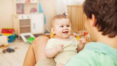 a man holding a baby in his lap and smiling at the child's face