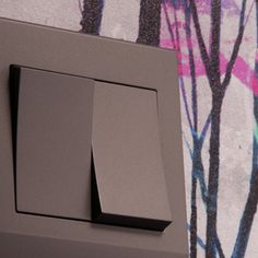 a close up of a wall switch with trees painted on the wall in the background