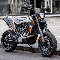 an orange and black motorcycle parked on the side of the road in front of a building