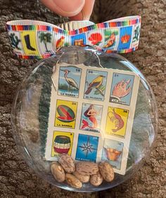 someone is holding a glass ornament with stamps on it and peanuts in the bottom