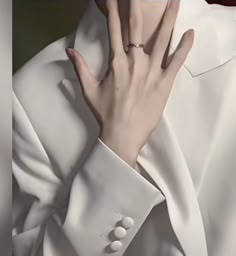 a close up of a person's hand with a ring on their finger, wearing a white suit