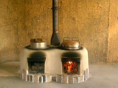 an old stove with two pots on top and a fire in the oven behind it