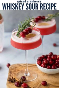 cranberry martini with rosemary garnish in coupe glasses on wooden cutting board