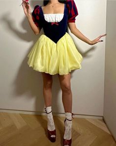 a woman dressed as snow white holding an apple in one hand and looking at the camera