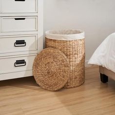 a wicker basket sitting next to a white bed