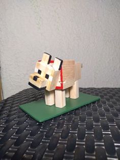 a small wooden toy horse on top of a green mat with white walls in the background