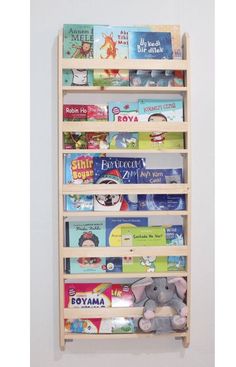 a wooden shelf with books and stuffed animals on the bottom shelves, against a white wall