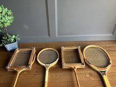 three tennis racquets sitting on the floor next to a potted plant