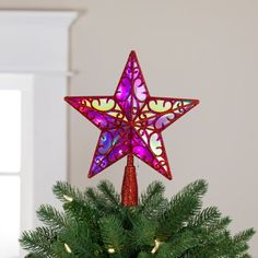 a star shaped ornament on top of a christmas tree