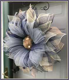 a blue and white mesh wreath hanging on the front door with a wooden button attached to it