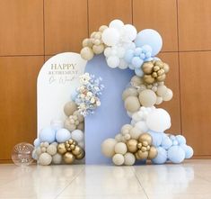 a blue and white balloon arch with flowers on it for a happy birthday party decoration