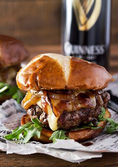 a sandwich with meat, cheese and lettuce on it next to a bottle of guinness