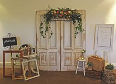 an old door is decorated with flowers and greenery in front of other antique items