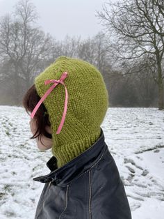 a woman wearing a green hat with a pink bow on it's head in the snow