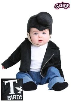 a baby sitting on the ground wearing a black hat and jacket with zippered sleeves