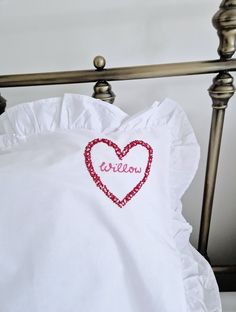 a white pillow with a red heart on it and the word willow written in cursive font