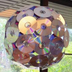 a bunch of cds that are hanging from a rack on a window sill in front of some trees