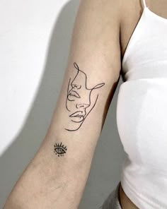 a woman's arm with a black line drawing of a face and an eye on it