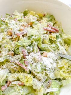 a white bowl filled with salad covered in parmesan cheese and lettuce