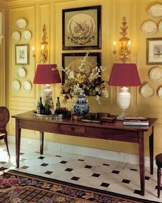 a table with two lamps and vases on it in a room filled with plates