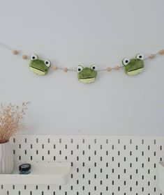 three stuffed frogs are hanging on the wall