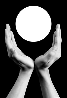 two hands holding an object in front of a white circle on a black background with space for text