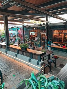 the inside of a restaurant with tables, benches and potted plants in front of it