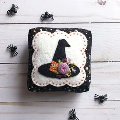 a small black and white patch with a witches hat on it, surrounded by spooky spider webs