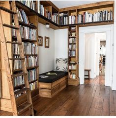 a room filled with lots of books next to a wooden ladder and bookcases