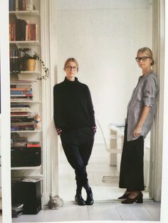 two women standing next to each other in front of a book shelf with books on it