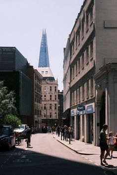 people are walking down the street near tall buildings